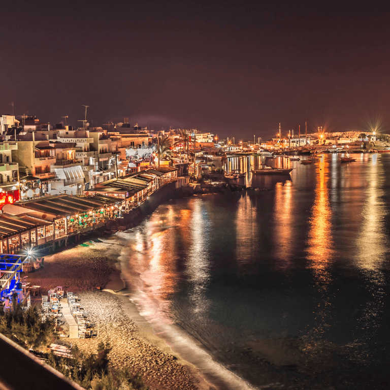 De belichte strip van Chersonissos in de nacht met op de achtergrond de zee